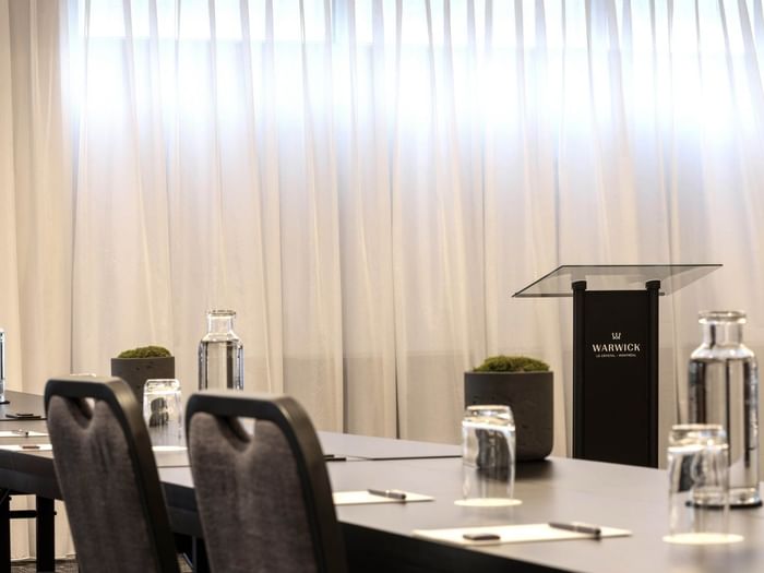 Black lectern with hotel branding by table settings in Salon René-Lévesque at Warwick Le Crystal Montreal