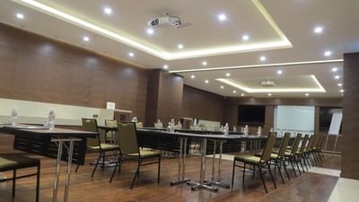 Aquamarin room set with tables, chairs, and a projector under bright lights at The Saujana Hotel Kuala Lumpur
