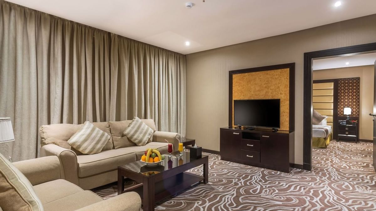 Junior Suite features Beige sofas by a coffee table with fruit under long curtains at Naviti by Warwick Al Khobar