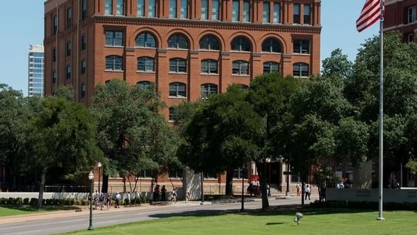 The historic red-brick building of the Sixth Floor Museum surrounded by trees near Warwick Melrose Hotel Dallas Ballroom