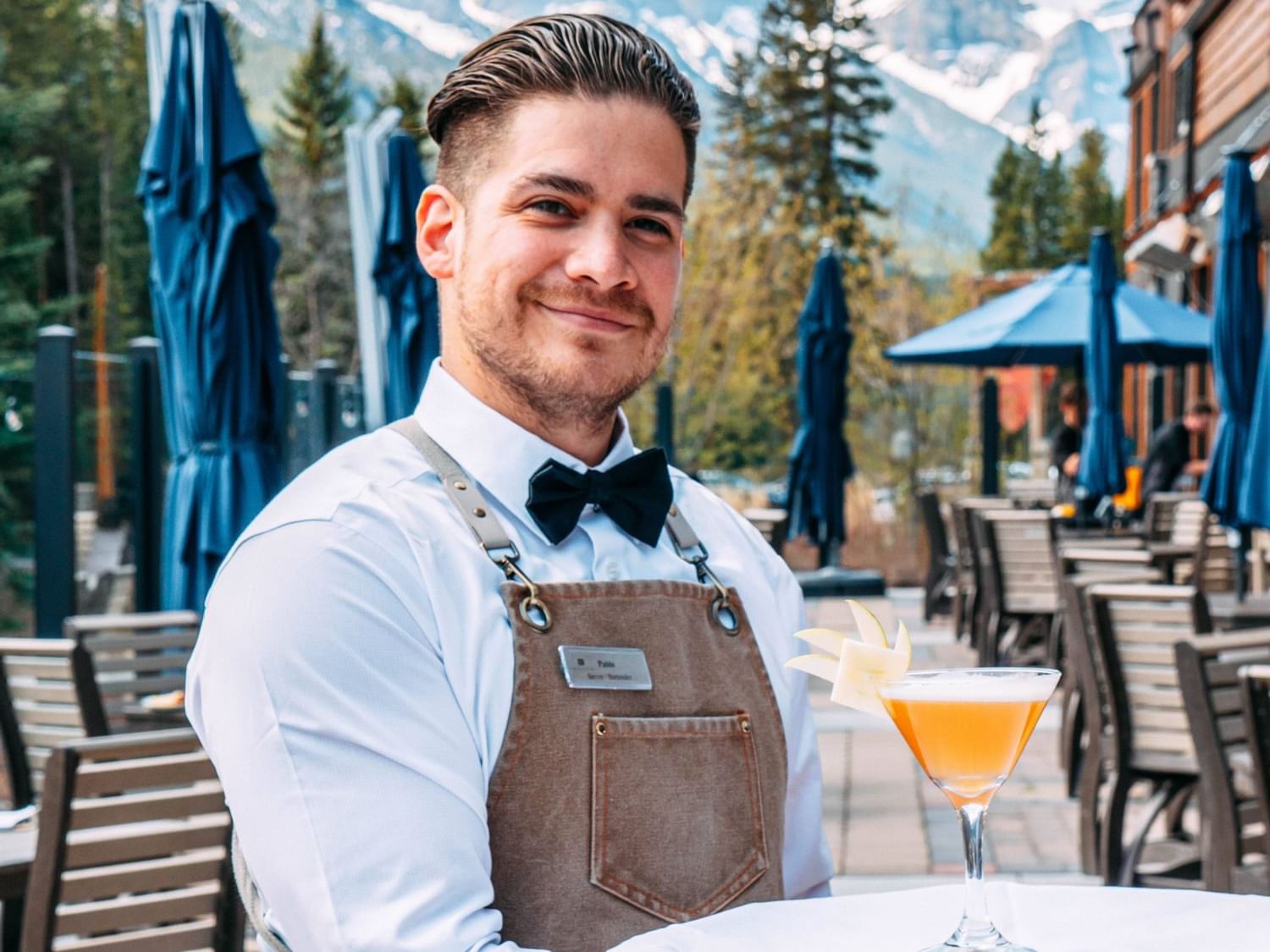 A waiter with a cocktail in Creekside Patio at Malcolm Hotel