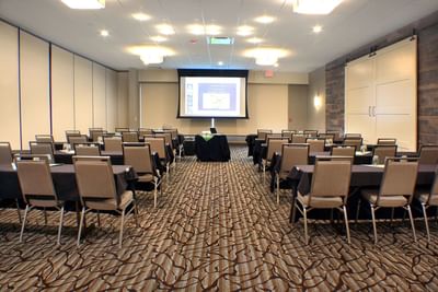 Conference room with rows of tables, chairs, and a projection screen, at Buffalo Bill Village