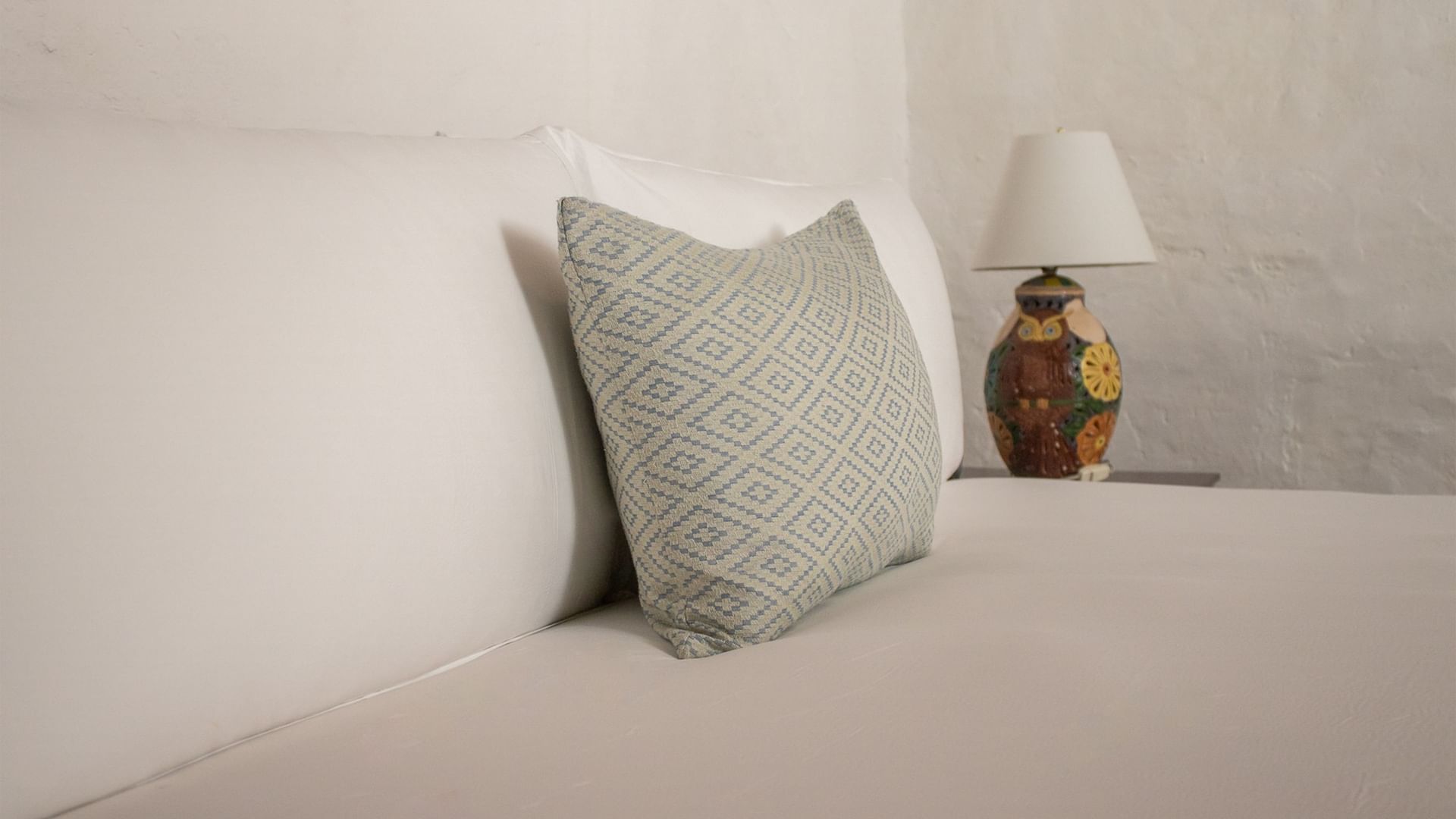 Cama con almohadas y lámpara en Suite Gobernador King de Quinta Real Oaxaca en Oaxaca de Juárez