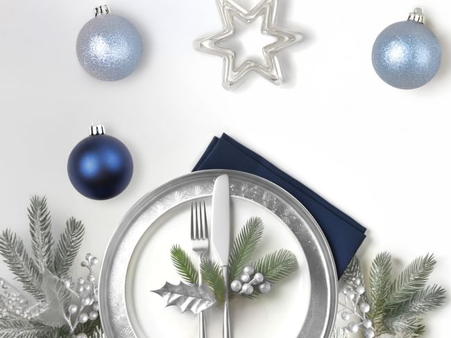 A festive Christmas Eve Dinner plate set with a knife, fork, and silver decor.