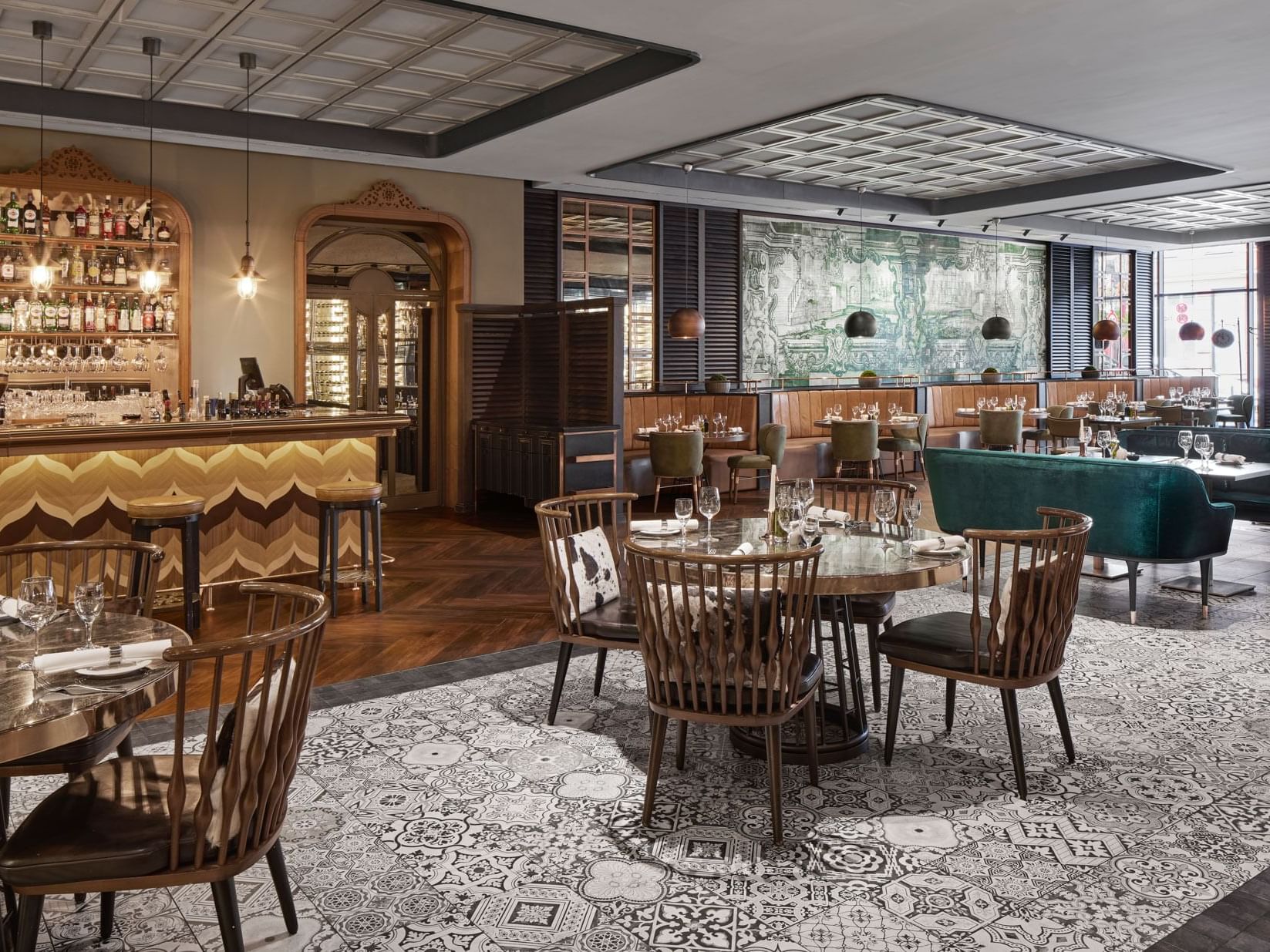 Elegantes Restaurant mit Tischen, Stühlen, Bar, Wandgemälden und gemustertem Teppich – Titanic Chaussee Berlin.