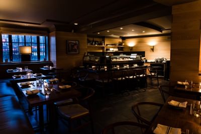 Dimly lit restaurant tables with place settings and sushi bar