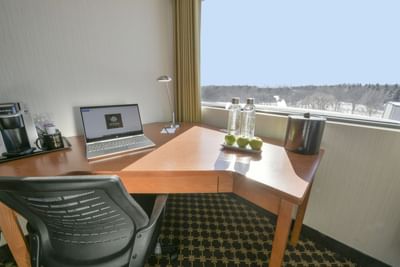 Laptop, bottled water and apples on desk.