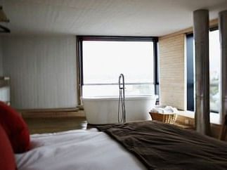 King bed & bathtub with ocean views in a bedroom at NOI Indigo 