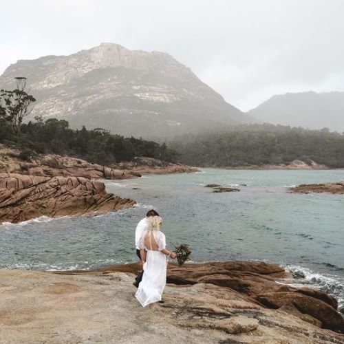 A wedded couple standing near the bay at Freycinet Lodge