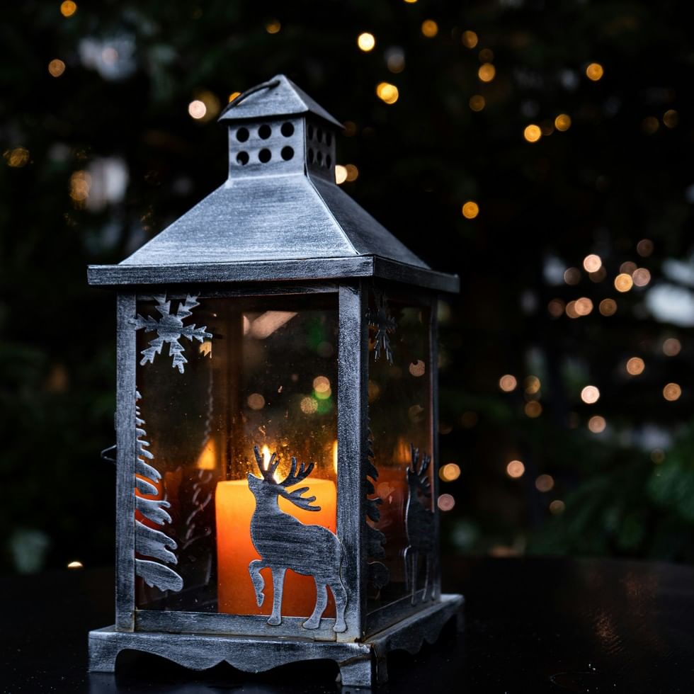 Dekorative Laterne mit Hirschmotiv und Kerze vor unscharfen Lichtern beim Mühlen Advent in Ramsau am Dachstein