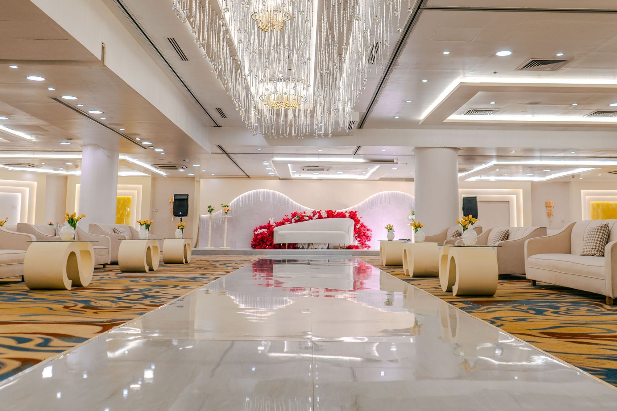Wedding hall with plush seating, reflective flooring, and floral arrangements at Dabab Hotel by Warwick - Riyadh