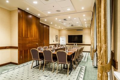 U-shaped table set up and TV in a meeting room at Polonia Palace Hotel