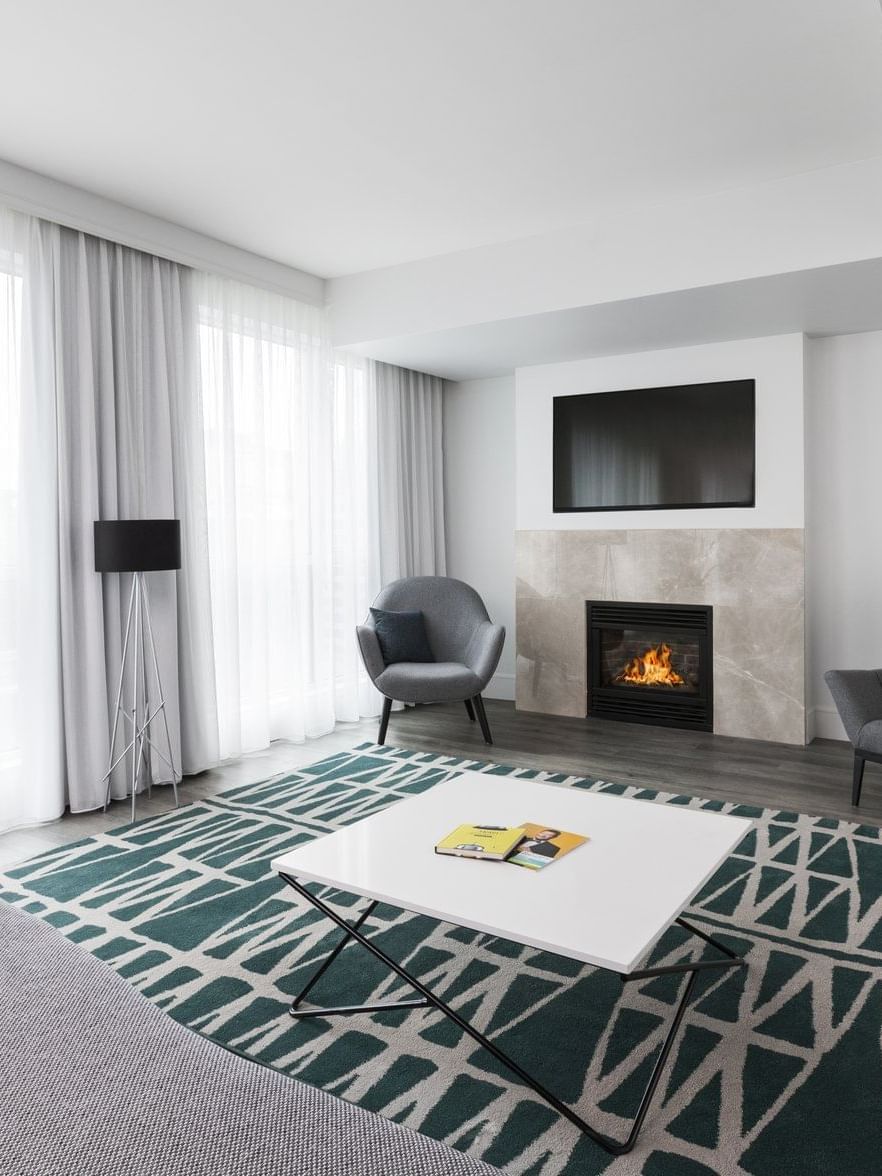 Salon moderne avec cheminée, canapé et fauteuils au Warwick Le Crystal – Montréal.
