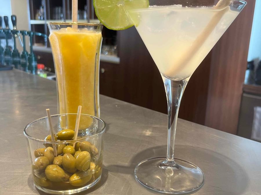 Cocktail, jus d'orange et olives vertes sur un comptoir au Yachtman.