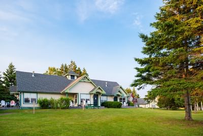 Cozy white cottages on a spacious green lawn at Rodd Brudenell River Resort, one of the premier places to stay in PEI
