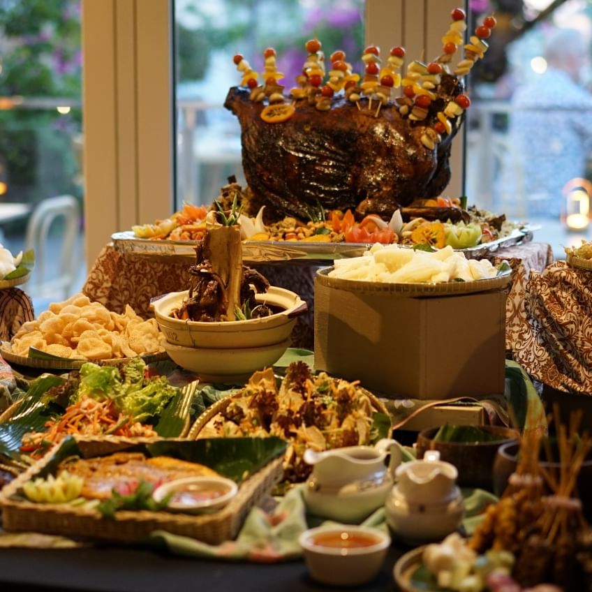 A table with a variety of food dishes and decorations for a buffet.