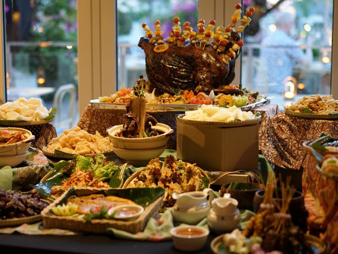 A table with a variety of food dishes and decorations for a buffet.