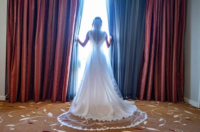 Bride opening the window curtains at Royal on the Park Hotel