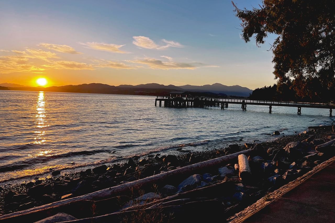 A wooden dock jutting out on the water under sunset