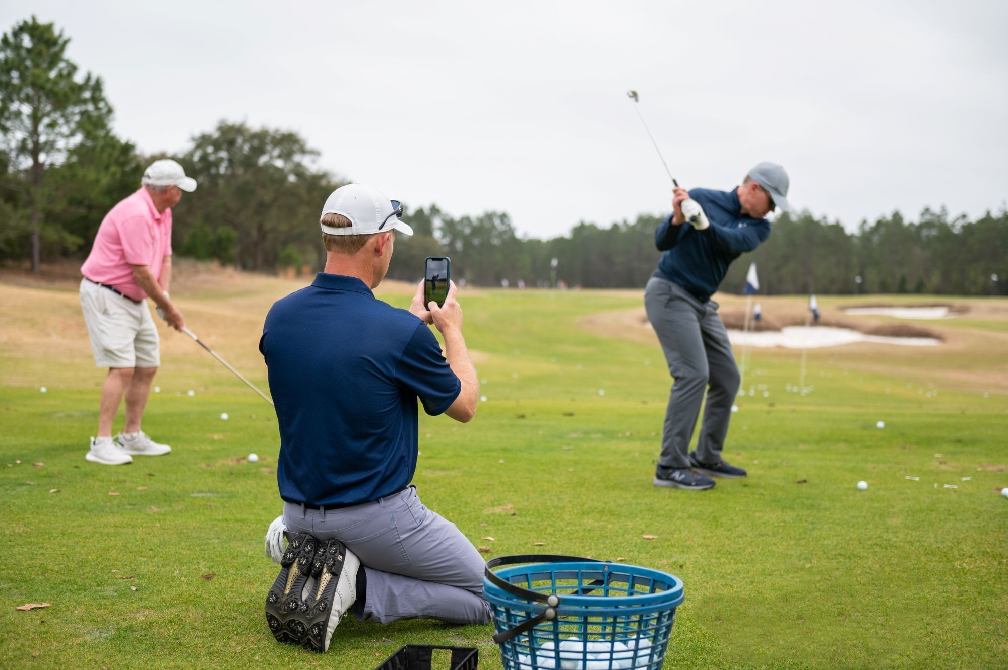 Three men playing golf on a course with one taking a picture at the Camp Creek Golf Performance Center
