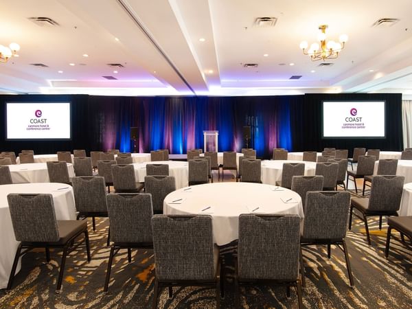 Conference room with round tables, chairs, and screens displays