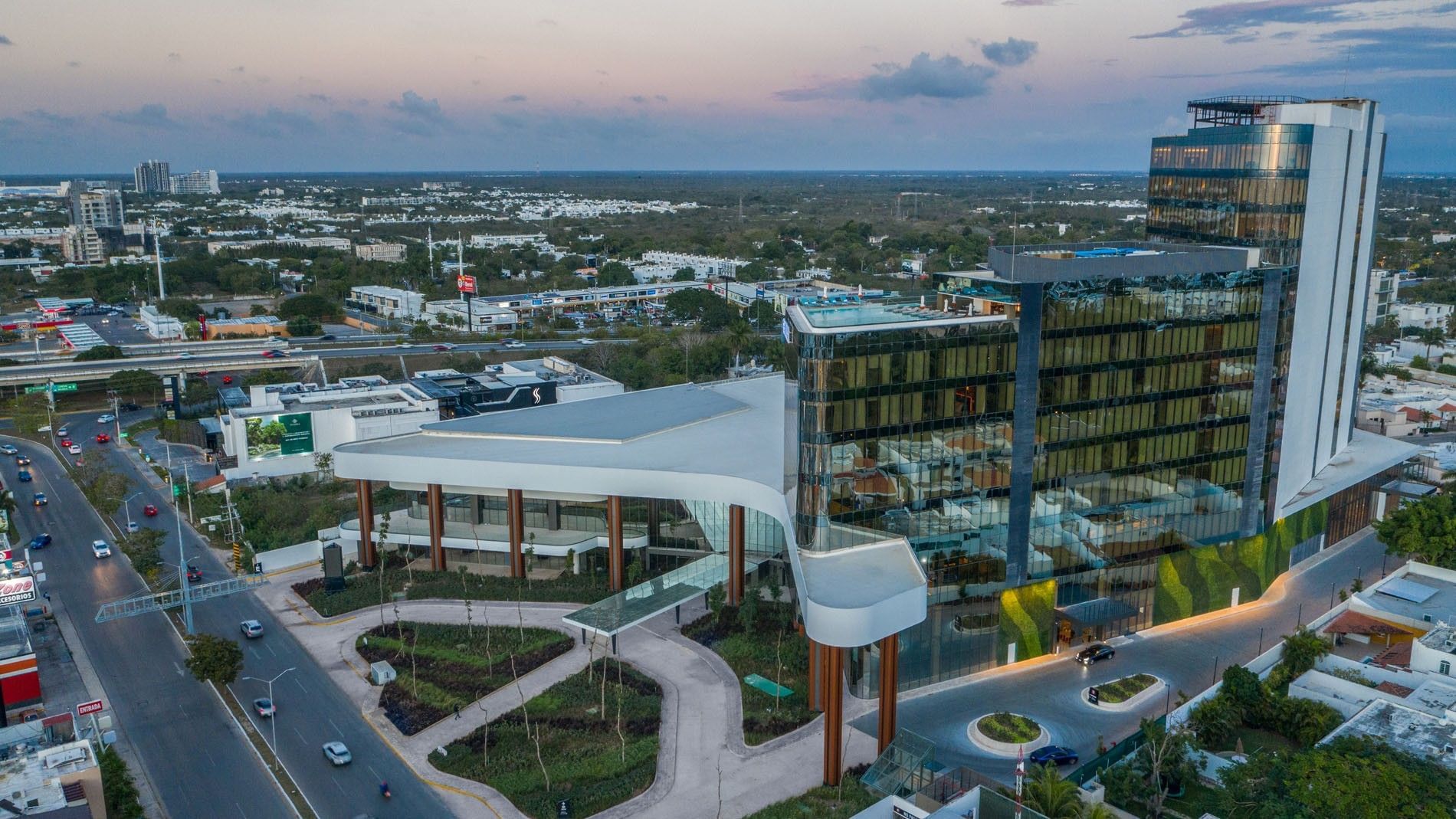 Wide aerial dusk shot of the Camino Real Merida hotel complex, featuring modern design and city streets