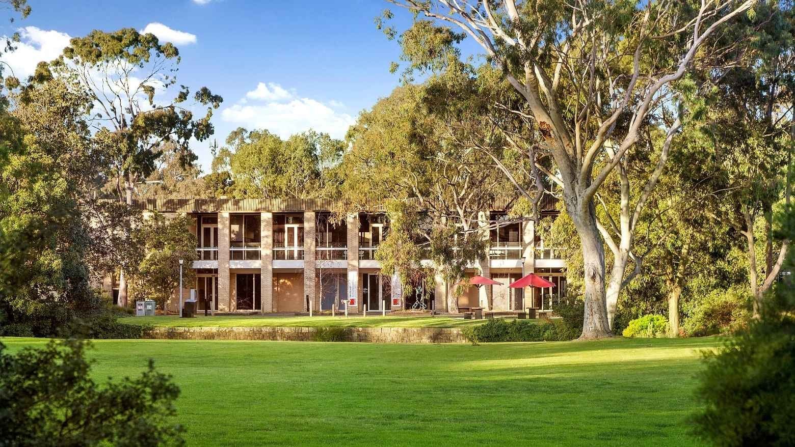 La Trobe University - Glenn College building with lush green lawn and trees.