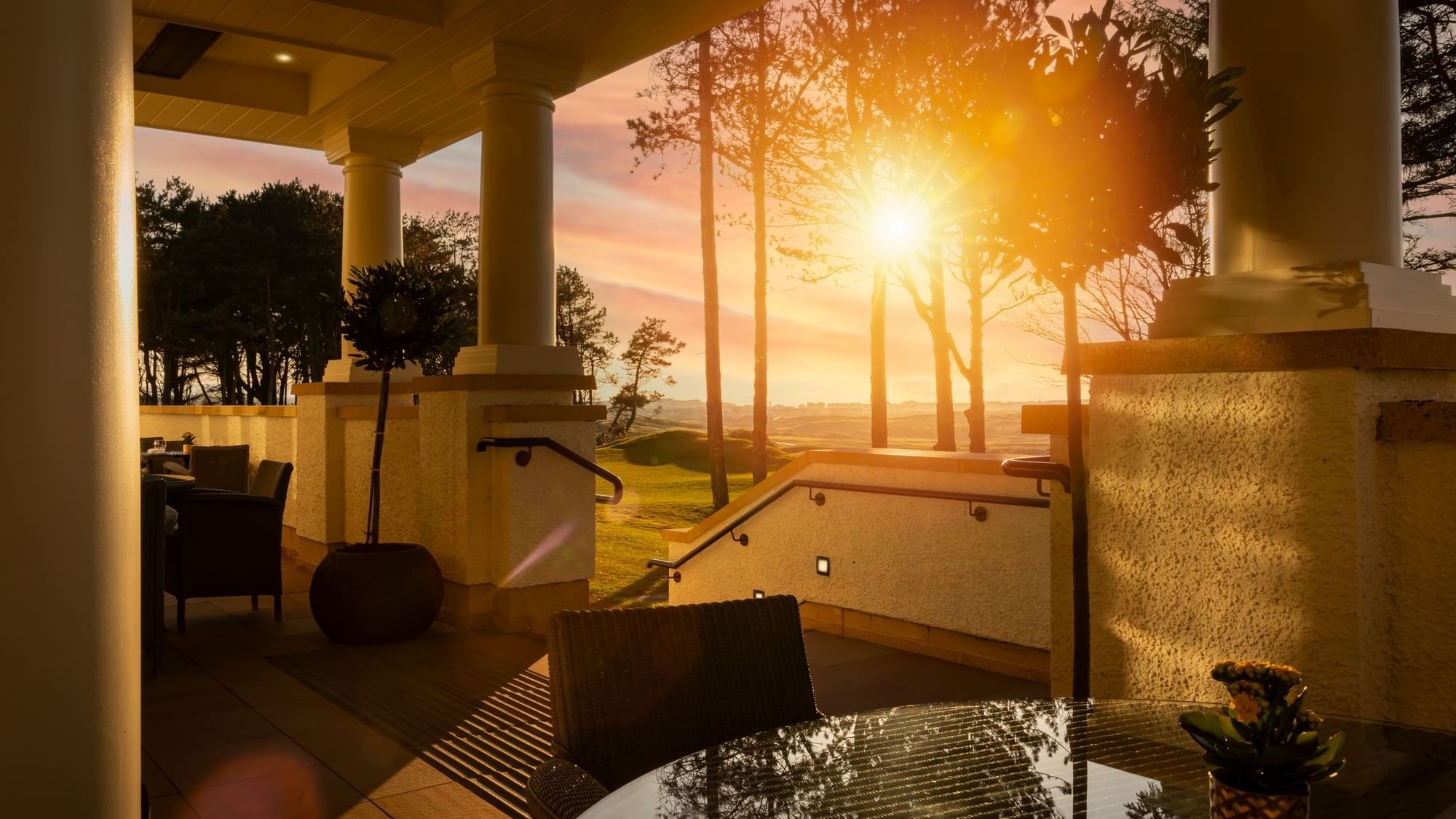 Stunning sunset view from the outdoor patio at Dunluce Lodge, overlooking a golf course and pine trees
