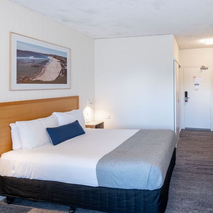 Clean, modern hotel room with white walls, bed, and artwork at Mercure Charlestown.