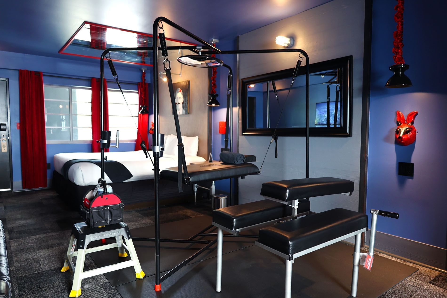 A hotel room with a bed, exercise equipment, and a TV on the wall.