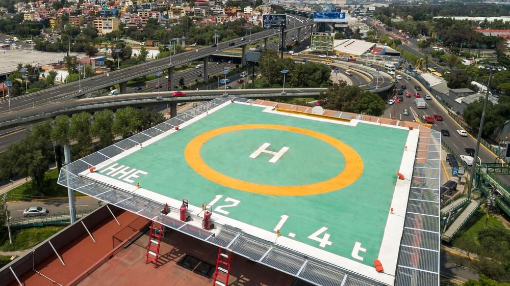 Rooftop helipad overlooking a busy highway and city landscape under a clear, bright sky at Real Inn Perinorte