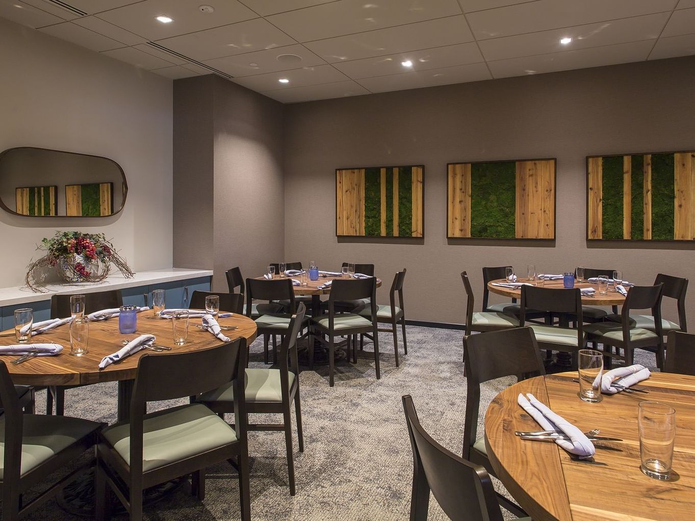 Round tables with place settings and wooden chairs in event rooms at Hotel Arista Naperville.