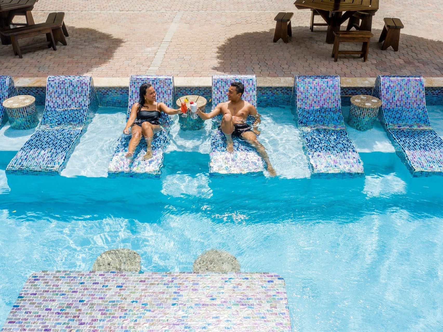 Couple relaxing & drinking cocktail in the pool of Eagle Aruba