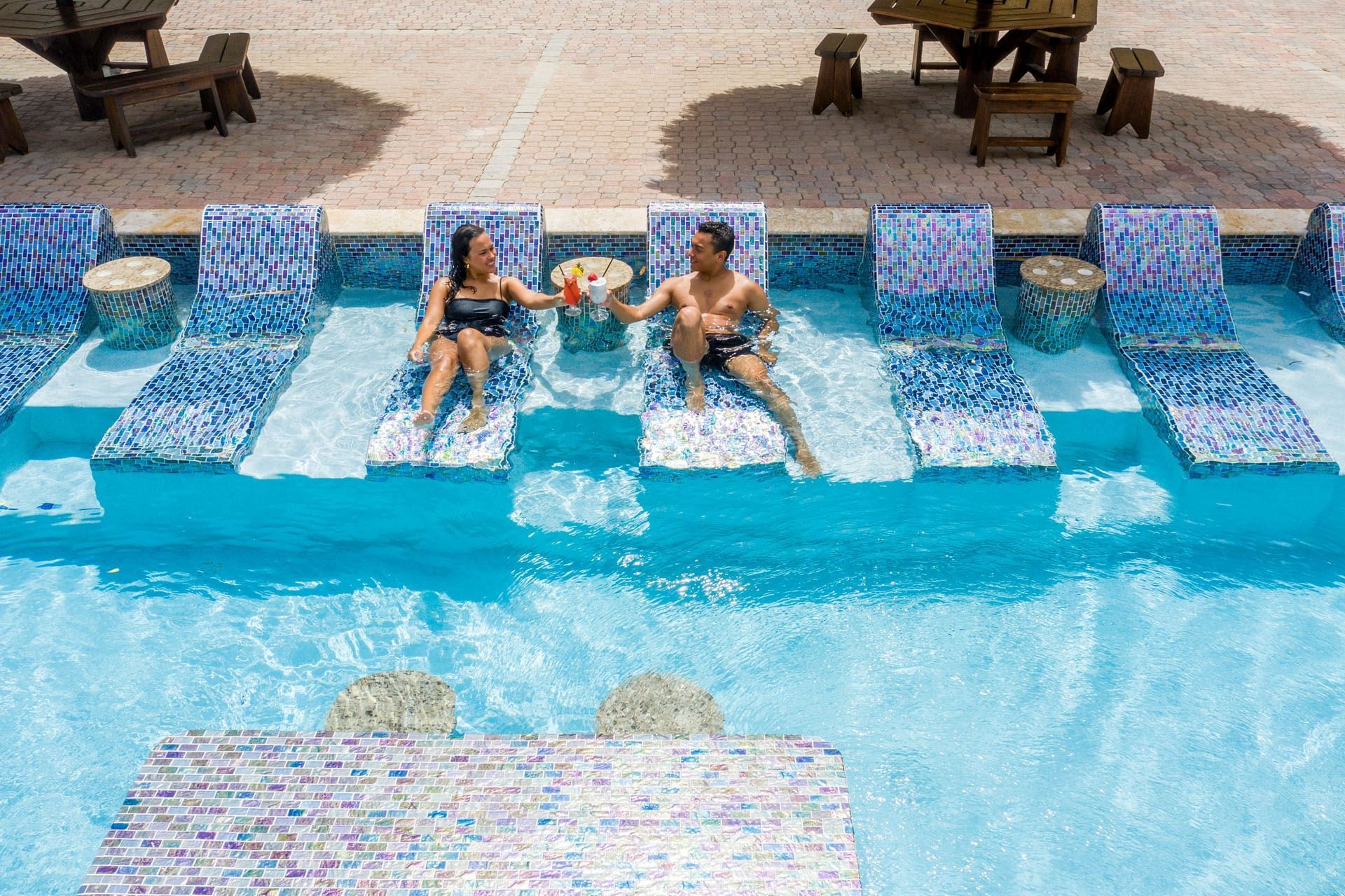 Couple relaxing & drinking cocktail in the pool of Eagle Aruba