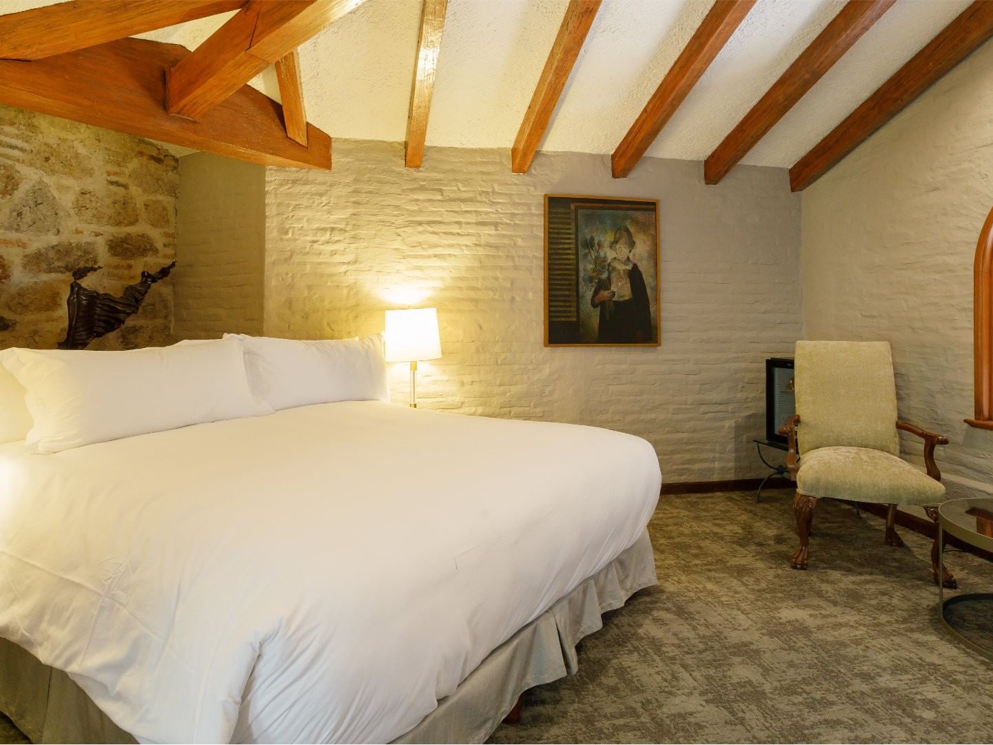 King Presidential Suite with vaulted wood beams and a white brick wall, located near the grand Quinta Real Guadalajara