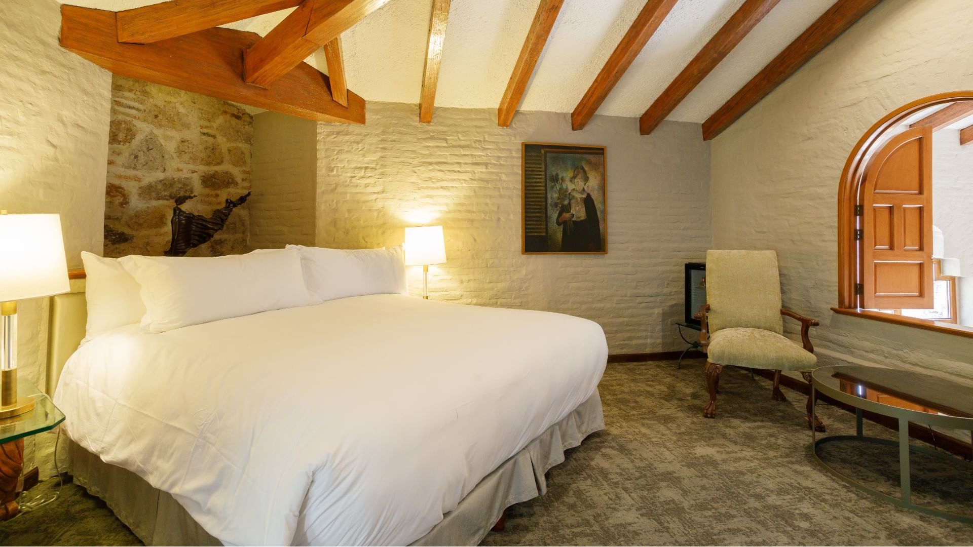 King Presidential Suite with vaulted wood beams and a white brick wall, located near the grand Quinta Real Guadalajara