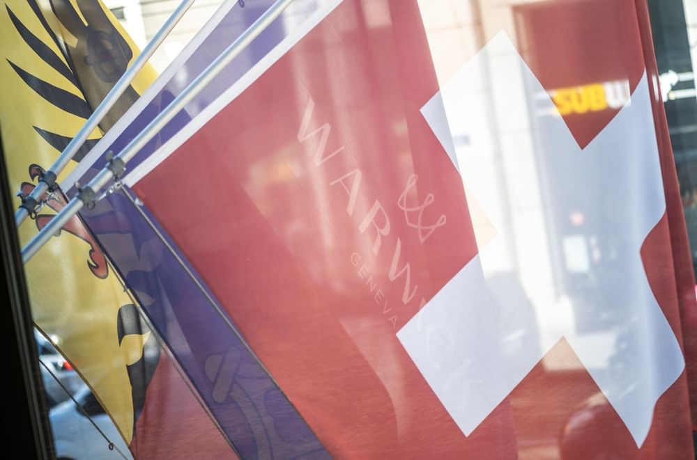 Swiss and Warwick flags by a window under a clear sky near Warwick Geneva