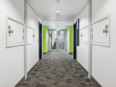Long hallway with patterned carpet and white doors at Student Living Auckland Anzac.