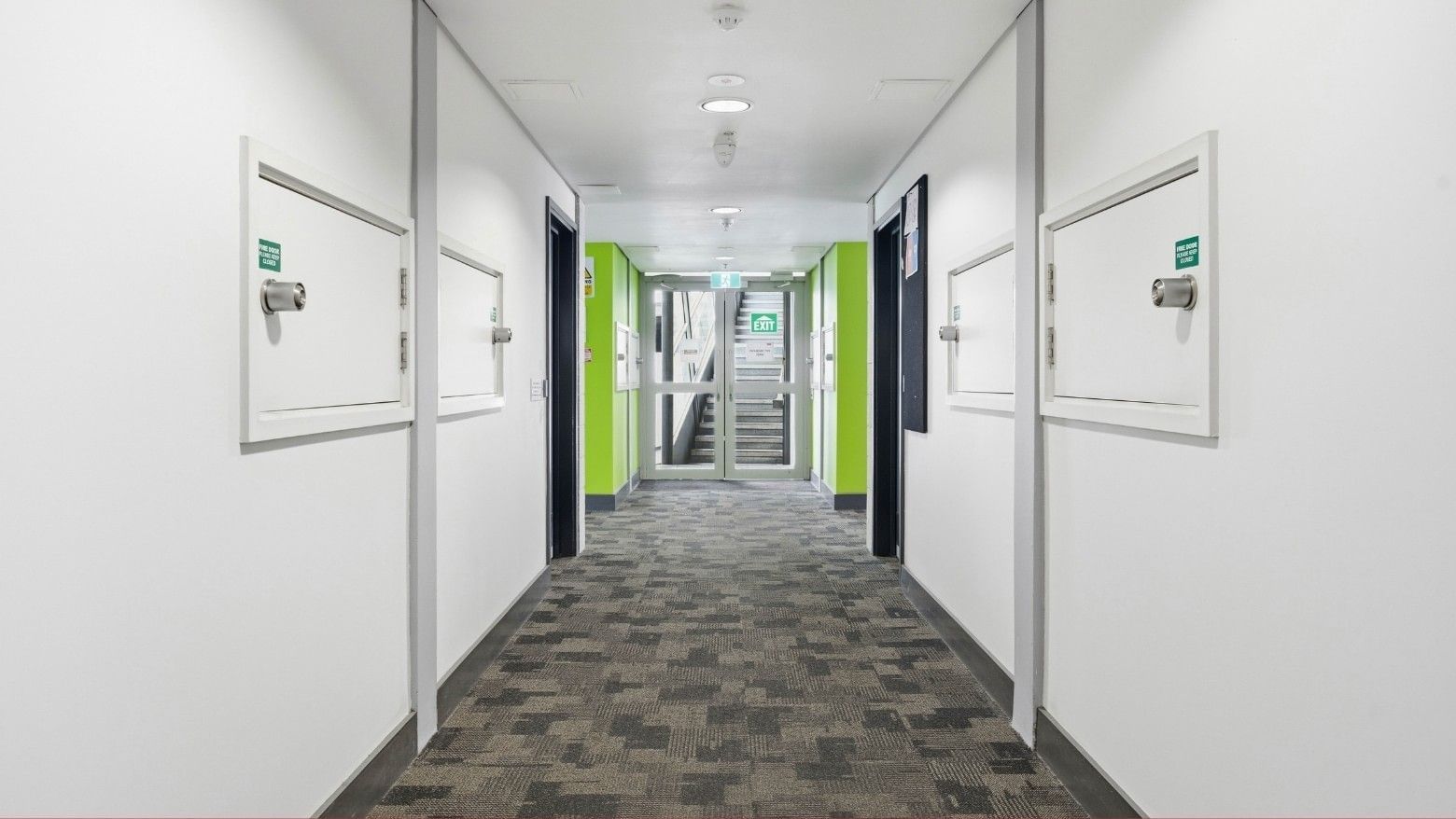 Long hallway with patterned carpet and white doors at Student Living Auckland Anzac.