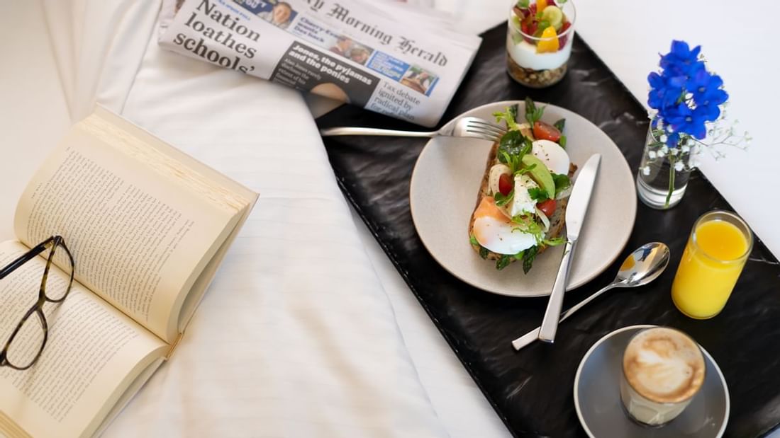 In-room breakfast setup with coffee, newspaper, and a healthy meal in Executive Room at Novotel Sydney International Airport