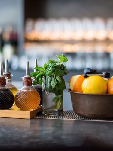 Bitters bottles by a bowl of citrus and fresh mint on a bar counter in The European at Warwick San Francisco