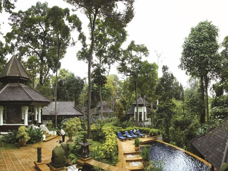 Pangkor Laut Resort’s tropical setting with a serene pool, sun loungers, and traditional architecture surrounded by trees
