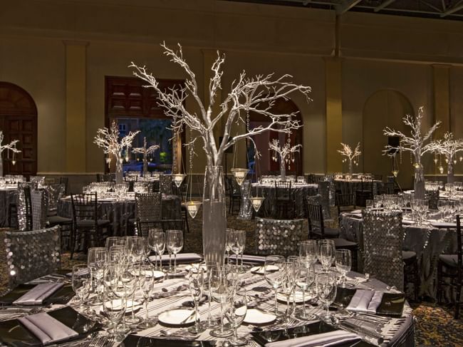 Elegantly set dining tables with silver decor and glass centerpieces in the Arcos 3 event room at Hacienda Del Mar Los Cabos in Cabo San Lucas.