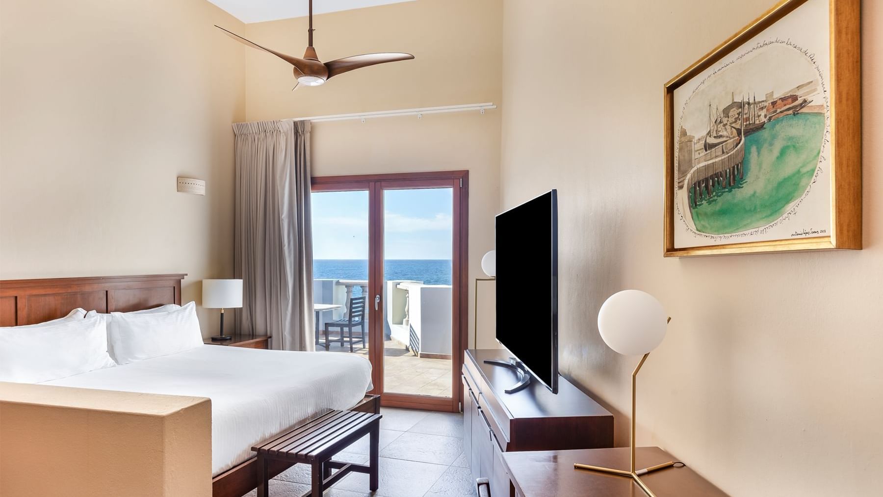 Comfortable room featuring a bed, TV, and a balcony with an ocean view at Curamoria Collection