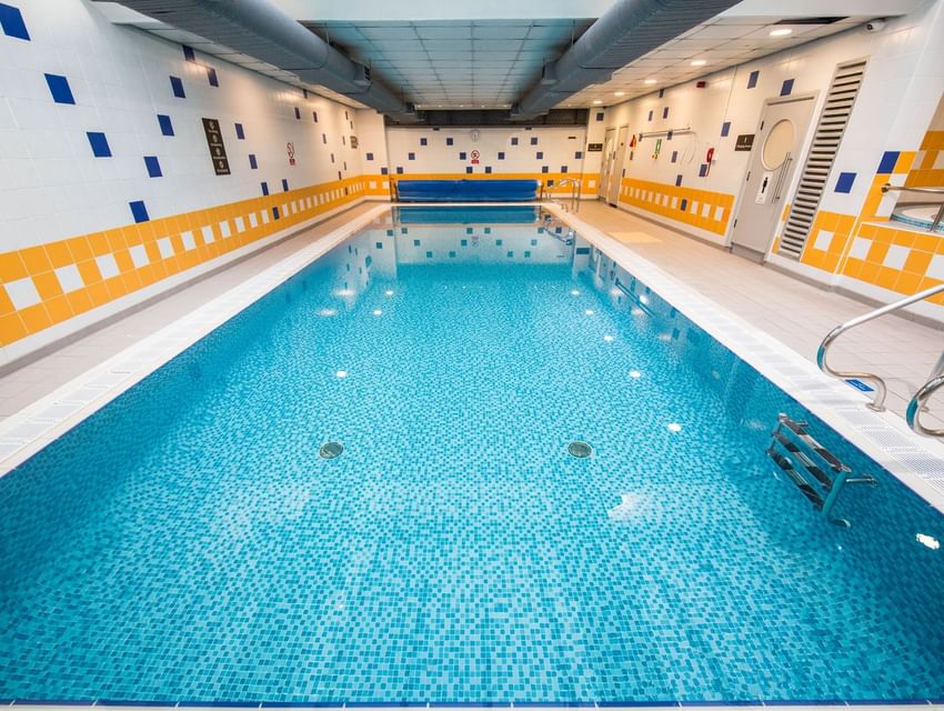 Indoor swimming pool with blue tiled water and poolside chairs at The Milner York