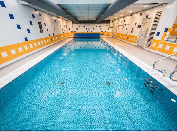 Indoor swimming pool with blue tiled water and poolside chairs at The Milner York