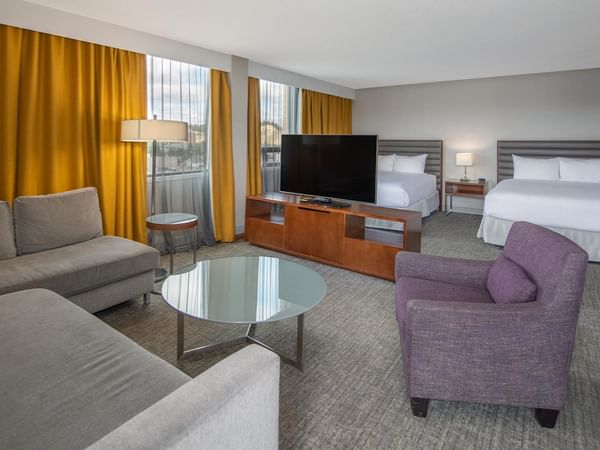 Spacious junior suite with two queen beds, seating area, and golden drapes at Coast Prince George Hotel in Prince George.