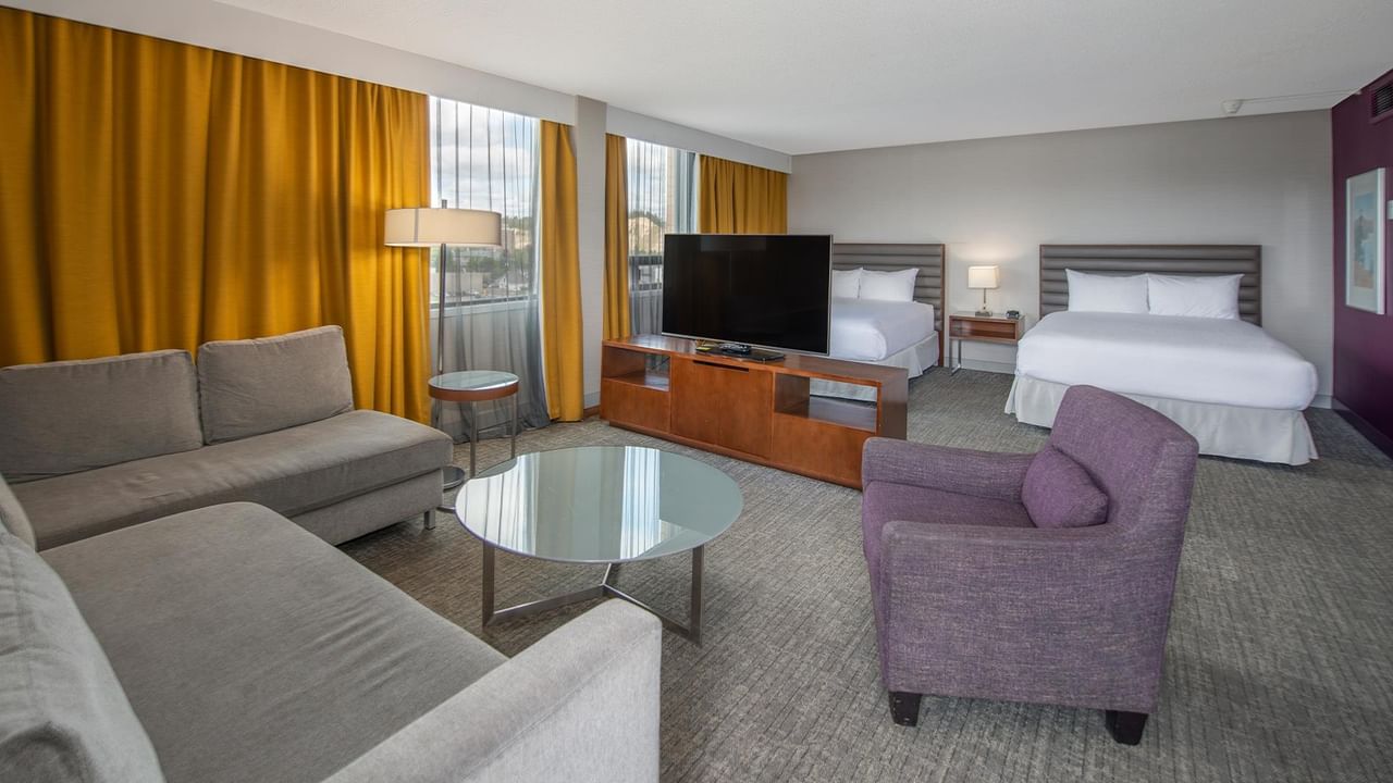 Spacious junior suite with two queen beds, seating area, and golden drapes at Coast Prince George Hotel in Prince George.