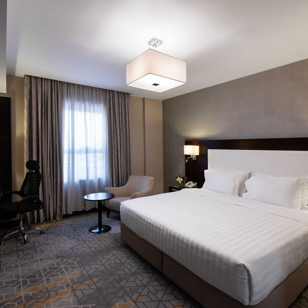 Work desk, nightstand, and cozy lounge chair by the bed in Executive Two-Bedroom Suite at Warwick Hotel Jeddah
