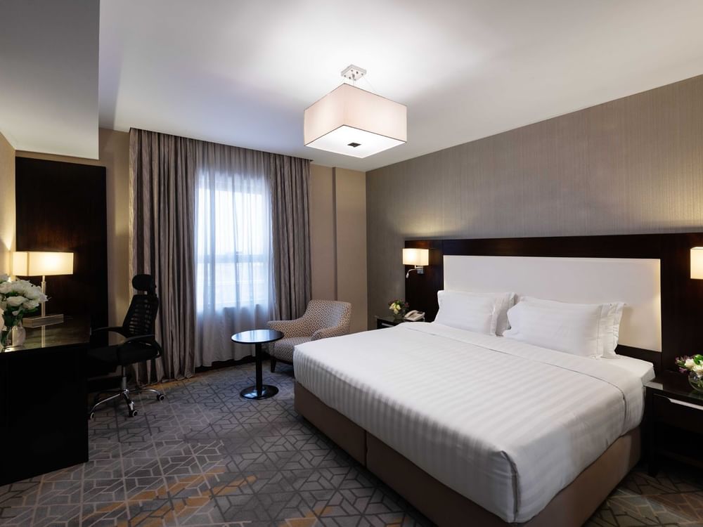 Work desk, nightstand, and cozy lounge chair by the bed in Executive Two-Bedroom Suite at Warwick Hotel Jeddah